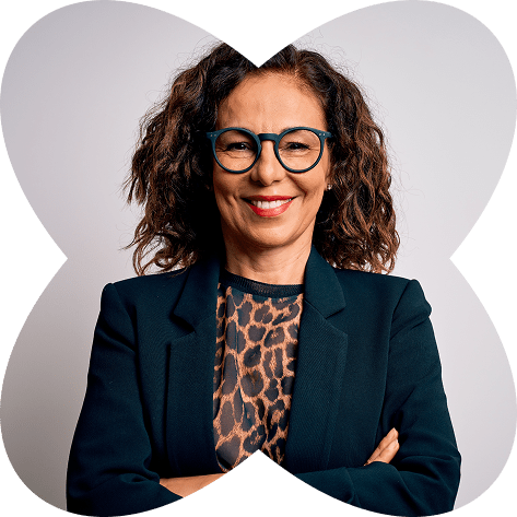 Confident woman with curly hair and glasses, smiling with arms crossed, framed by a floral graphic and wearing a dark blazer.